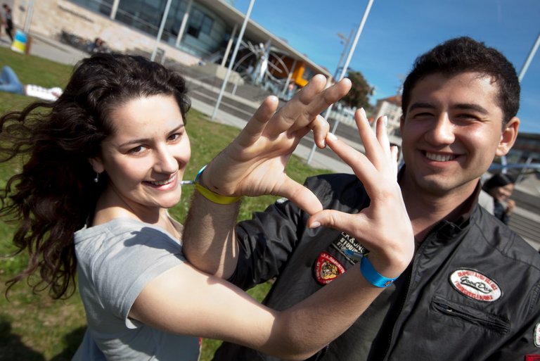 zwei Studierende die zusammen mit ihren Fingern ein Herz formen